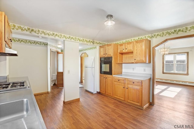 kitchen with light hardwood / wood-style flooring, black oven, white refrigerator, stainless steel gas cooktop, and a baseboard radiator