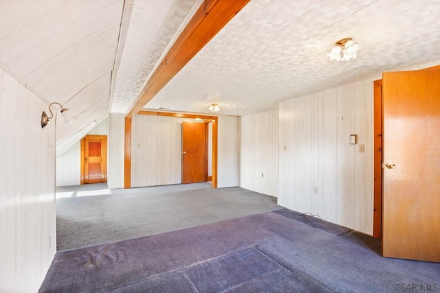 carpeted spare room featuring a textured ceiling and wood walls