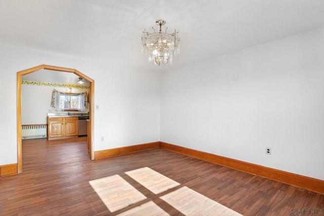 empty room with an inviting chandelier, radiator, and dark hardwood / wood-style floors