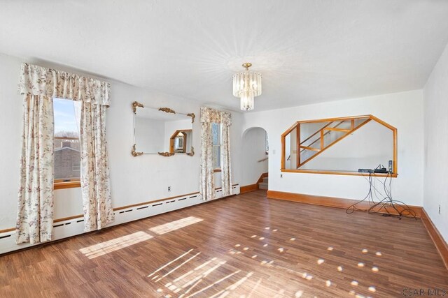 interior space featuring hardwood / wood-style flooring, an inviting chandelier, and a baseboard heating unit