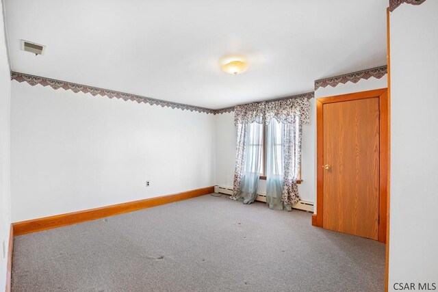 spare room with a baseboard heating unit and light colored carpet