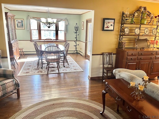 dining room featuring a baseboard heating unit, baseboard heating, an inviting chandelier, and dark wood finished floors