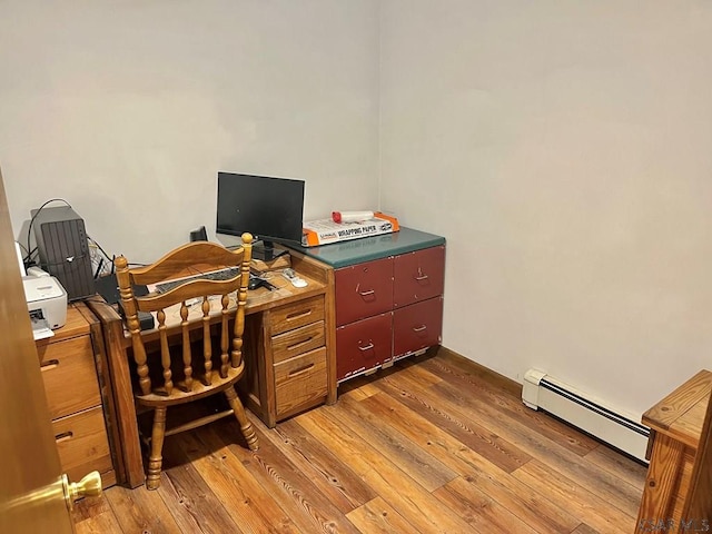 office space featuring a baseboard heating unit and light wood-style floors