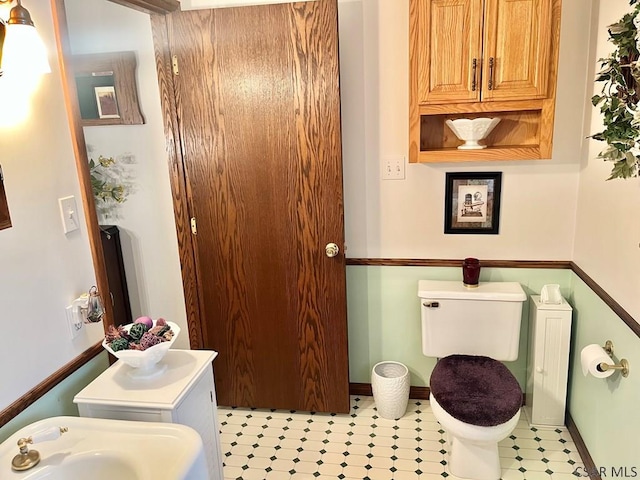 bathroom featuring toilet, baseboards, and a sink