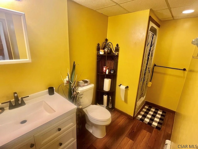 full bathroom with vanity, a shower with shower curtain, wood finished floors, a drop ceiling, and toilet