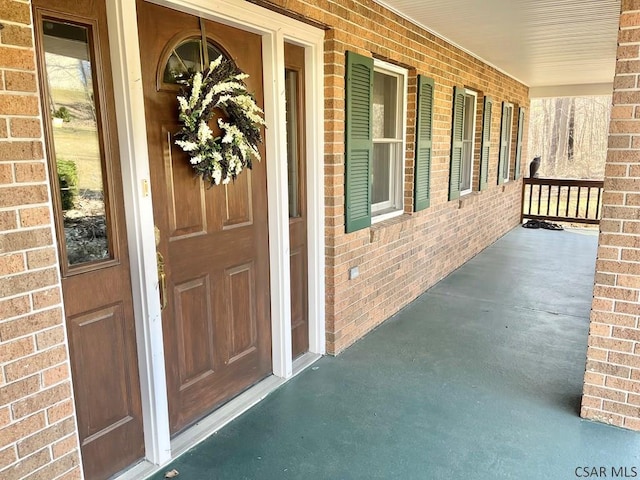 doorway to property with covered porch and brick siding