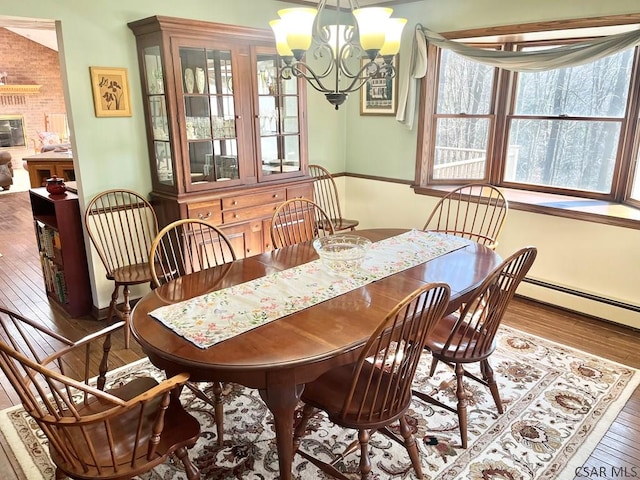 dining space featuring hardwood / wood-style floors, a baseboard heating unit, and a chandelier