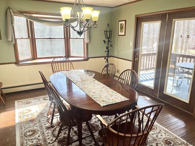 dining area with a baseboard heating unit, hardwood / wood-style flooring, and an inviting chandelier