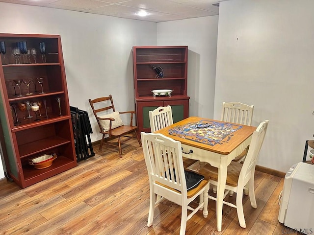 dining area with a paneled ceiling, baseboards, and wood-type flooring