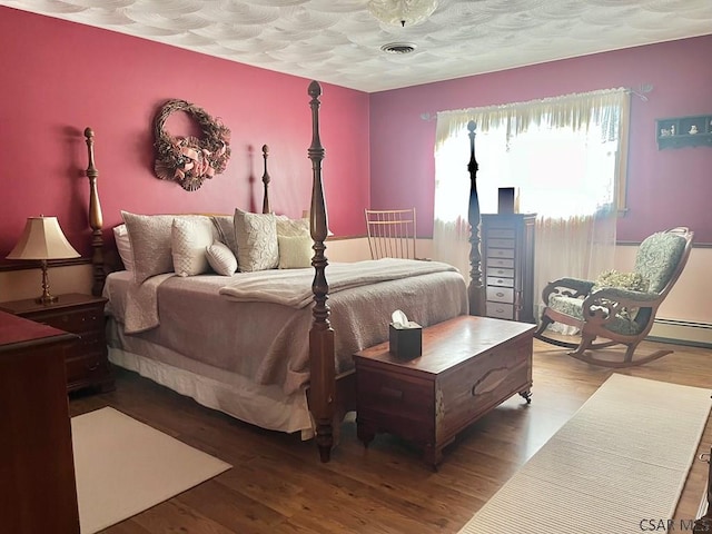 bedroom featuring visible vents, a textured ceiling, and wood finished floors