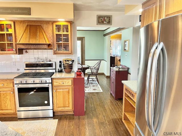 kitchen featuring premium range hood, dark wood-style flooring, glass insert cabinets, appliances with stainless steel finishes, and tasteful backsplash