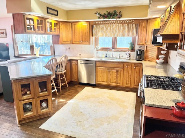 kitchen with a sink, light stone counters, tasteful backsplash, appliances with stainless steel finishes, and brown cabinetry