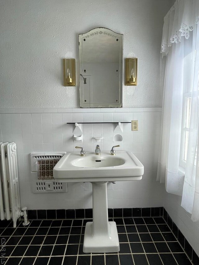 bathroom with tile patterned floors, radiator, and tile walls