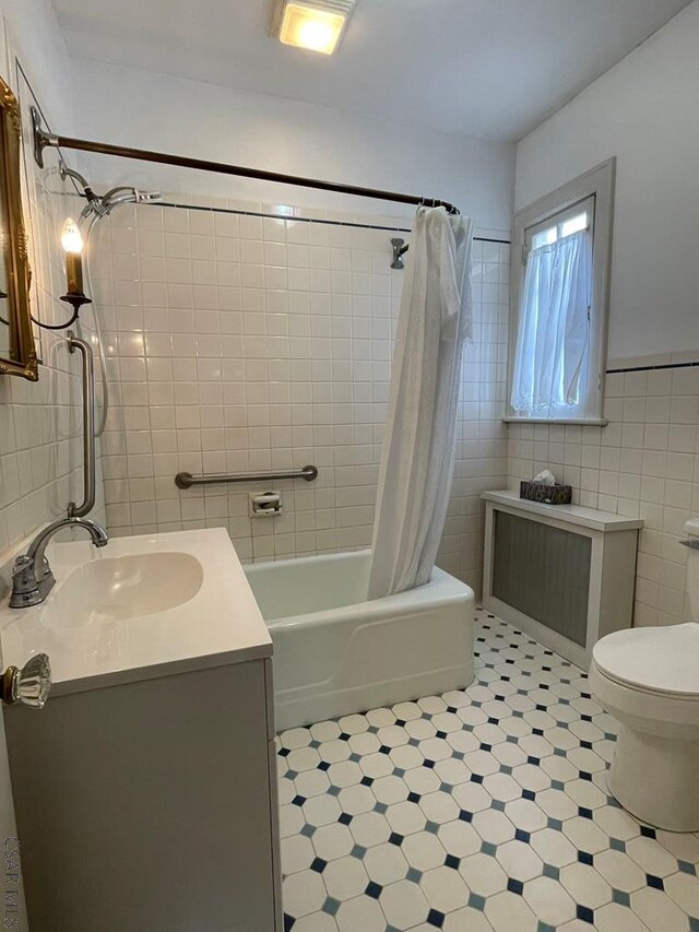 full bathroom featuring toilet, vanity, shower / bathtub combination with curtain, and tile walls