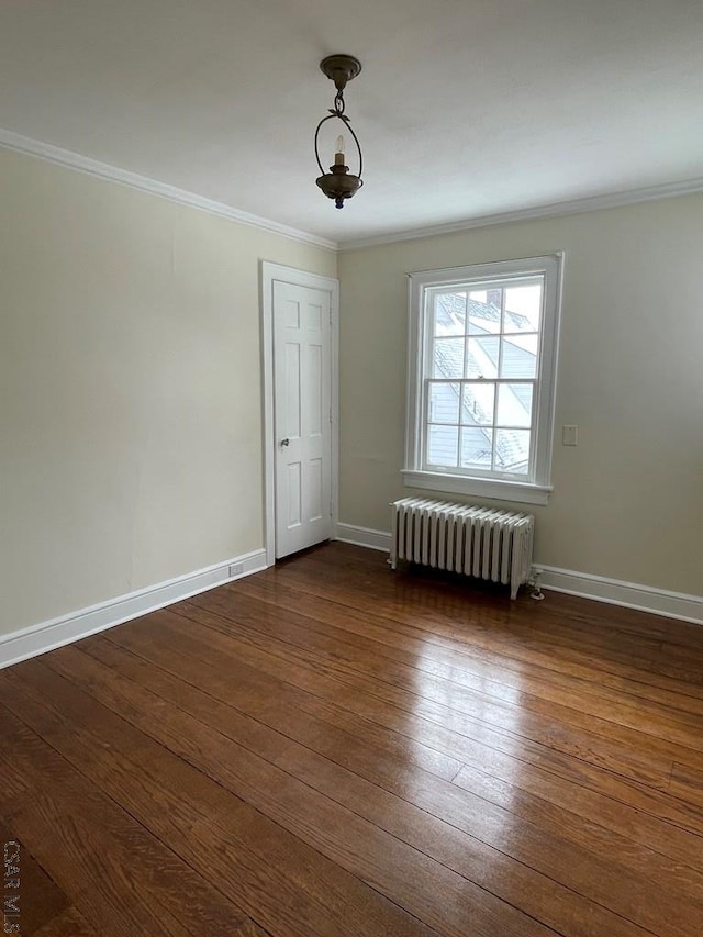 empty room featuring ornamental molding, dark wood-type flooring, and radiator heating unit