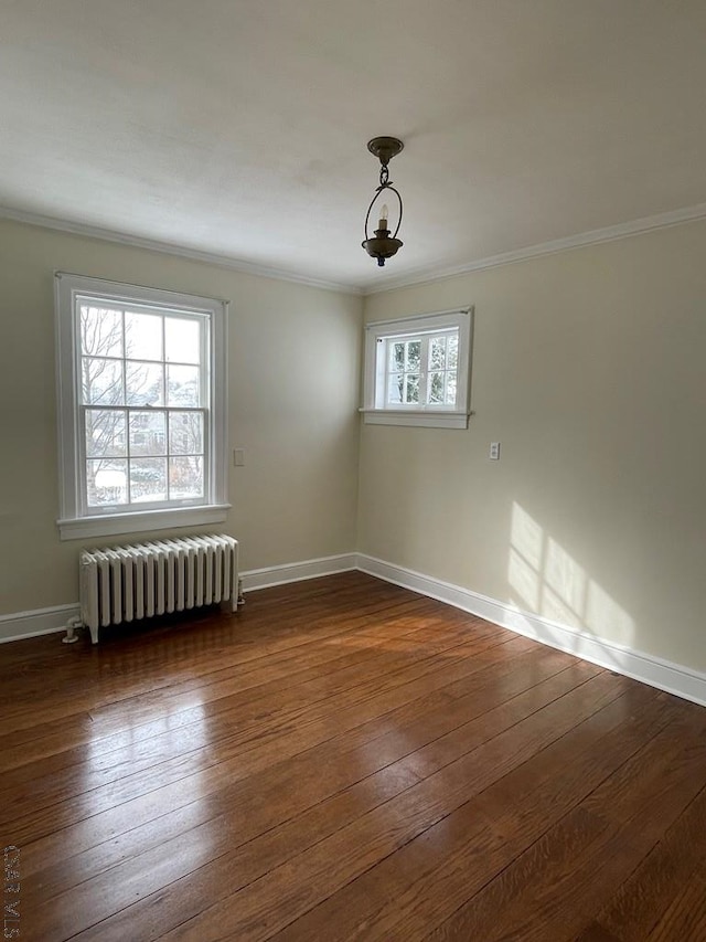 empty room with crown molding, plenty of natural light, radiator, and dark hardwood / wood-style floors