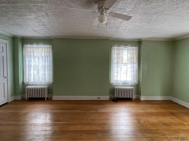 spare room featuring ceiling fan, ornamental molding, wood-type flooring, and radiator