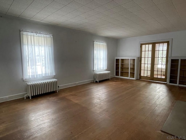 empty room featuring radiator heating unit, dark hardwood / wood-style flooring, and a wealth of natural light