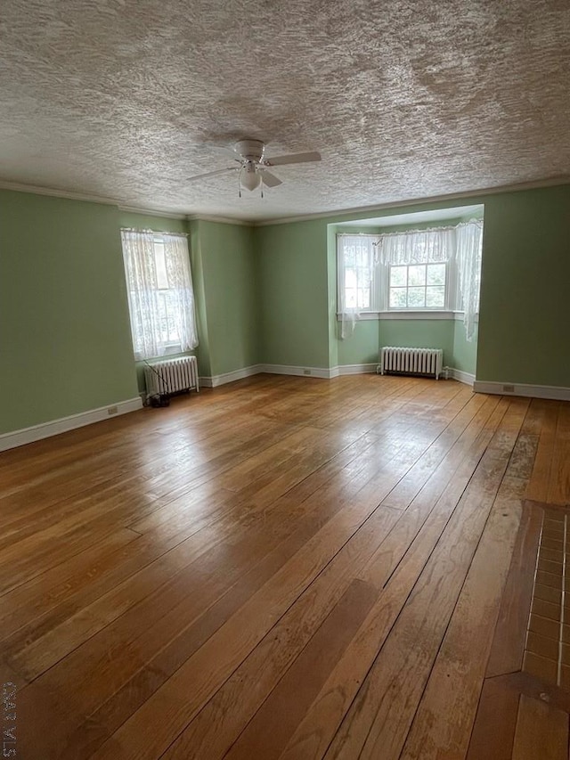 empty room with ceiling fan, radiator heating unit, and light wood-type flooring