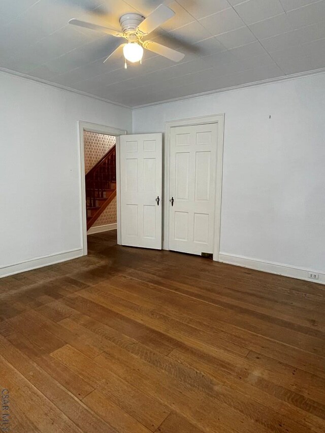 unfurnished bedroom featuring dark hardwood / wood-style flooring, crown molding, and ceiling fan