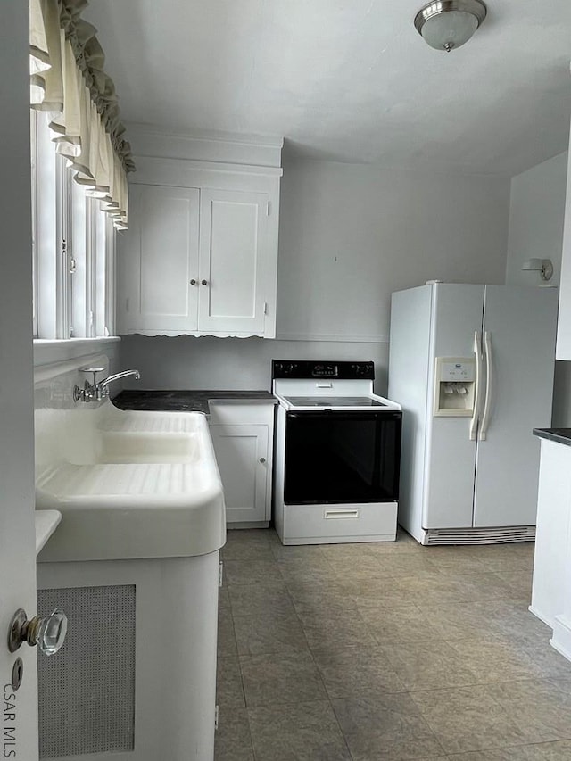 kitchen with range with electric stovetop, white refrigerator with ice dispenser, sink, and white cabinets