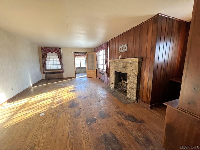 unfurnished living room featuring wood-type flooring, radiator heating unit, and a fireplace