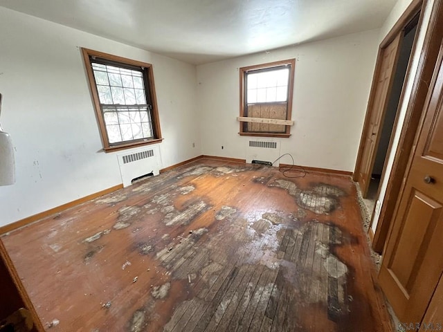 unfurnished bedroom featuring wood-type flooring, radiator, and multiple windows