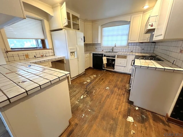 kitchen featuring dishwasher, white refrigerator with ice dispenser, tile counters, and white cabinets