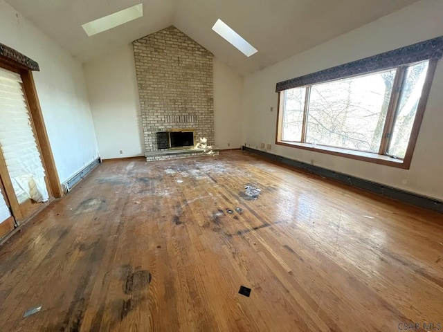 unfurnished living room featuring hardwood / wood-style floors, a fireplace, lofted ceiling with skylight, and a baseboard heating unit