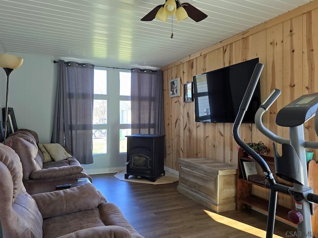 living room featuring ceiling fan, wood walls, dark hardwood / wood-style flooring, and a wood stove