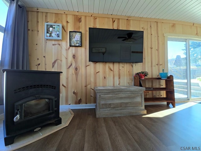 living room featuring wooden walls, dark hardwood / wood-style floors, and a wood stove