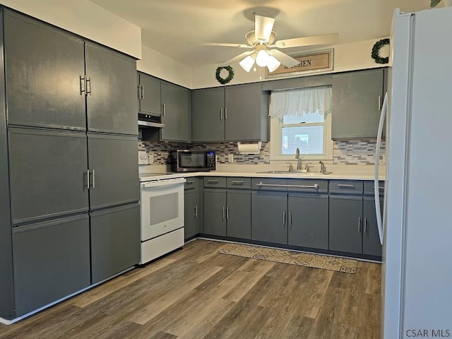 kitchen with sink, white appliances, ceiling fan, dark hardwood / wood-style floors, and decorative backsplash