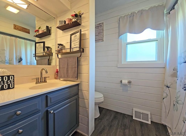 bathroom featuring hardwood / wood-style flooring, vanity, toilet, and wood walls