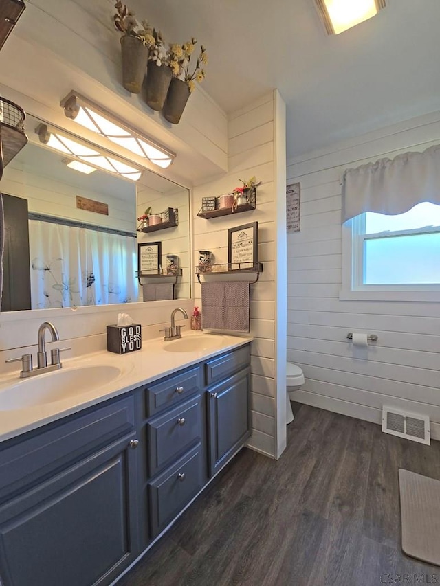 bathroom featuring vanity, wood-type flooring, toilet, and wood walls