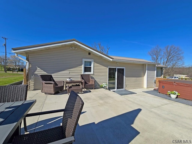 rear view of property with a hot tub, a patio, and outdoor lounge area