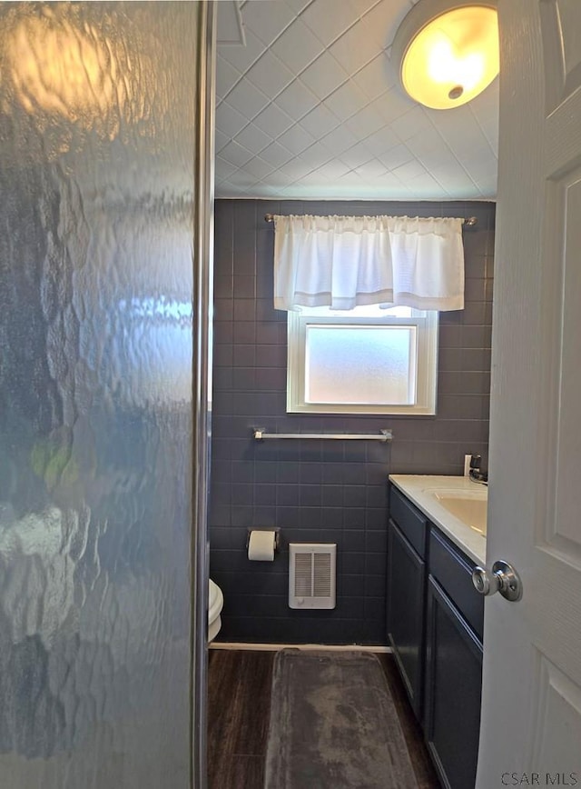 bathroom with vanity, hardwood / wood-style flooring, toilet, and tile walls