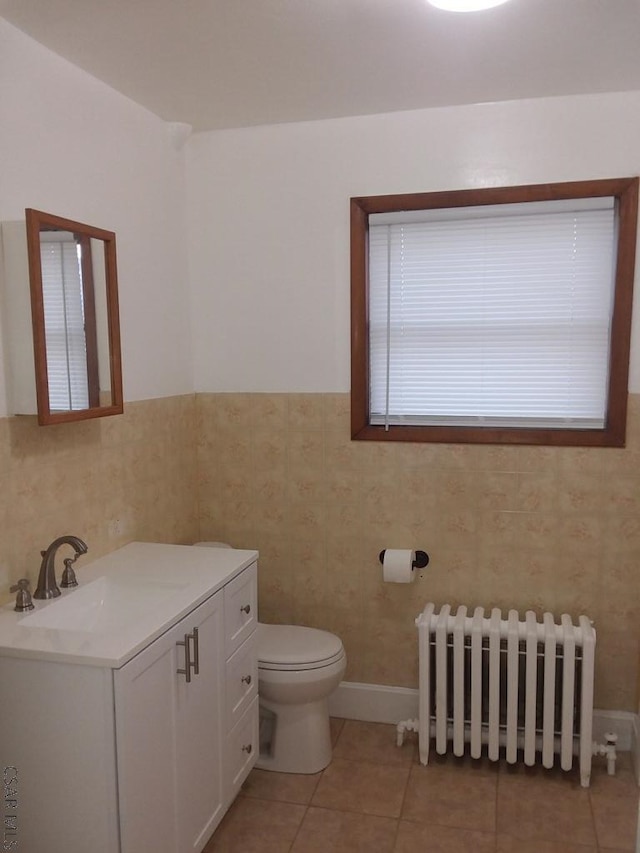 bathroom with radiator, tile walls, tile patterned flooring, vanity, and toilet