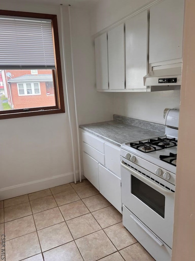 kitchen featuring light tile patterned floors, white cabinets, and white gas range oven