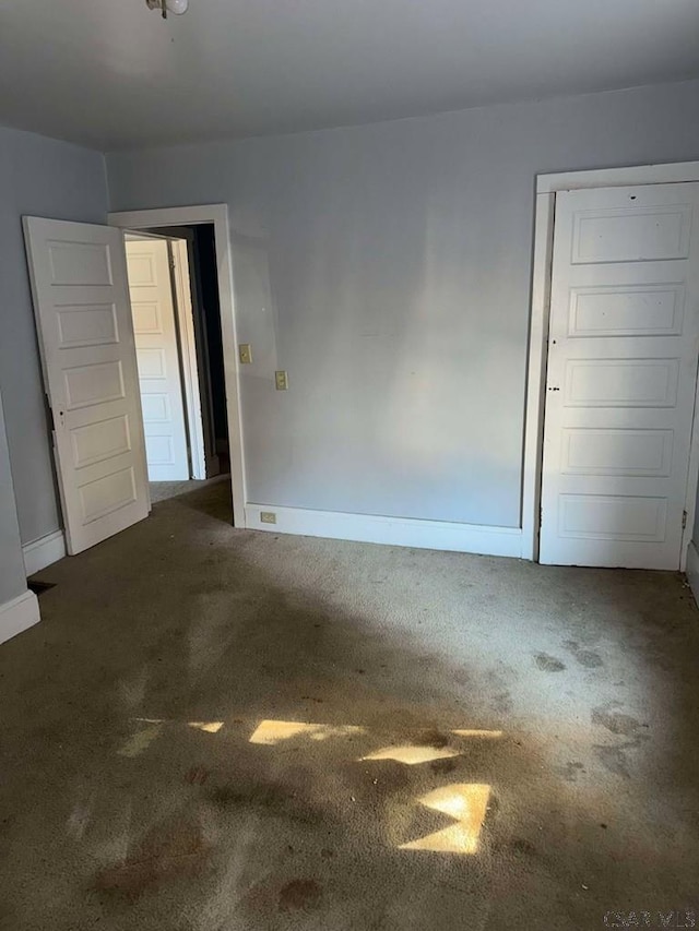 spare room with dark colored carpet and baseboards