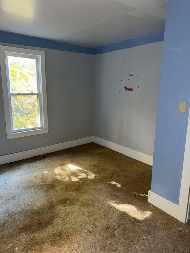 empty room featuring baseboards and dark carpet