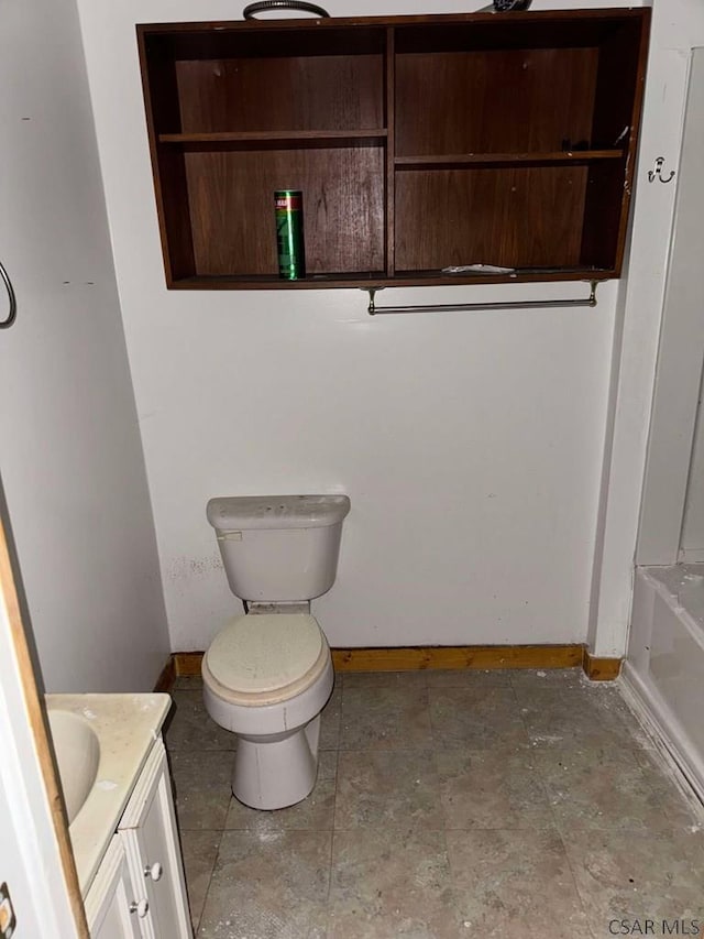 full bath with a tub to relax in, toilet, vanity, and baseboards