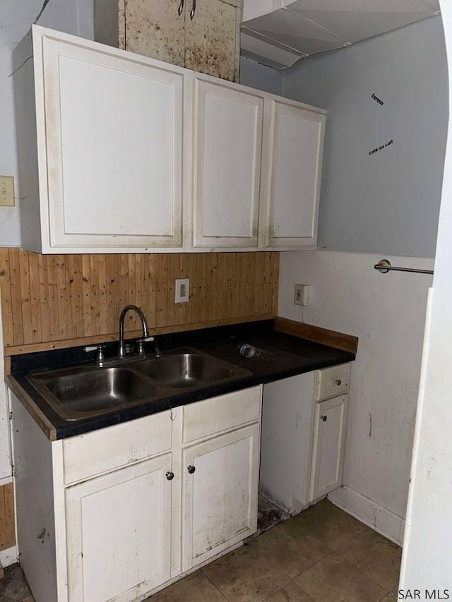 kitchen featuring dark countertops, white cabinetry, and a sink