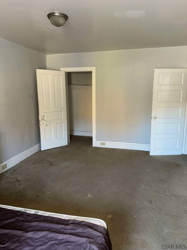 unfurnished bedroom featuring a closet, unfinished concrete flooring, and baseboards