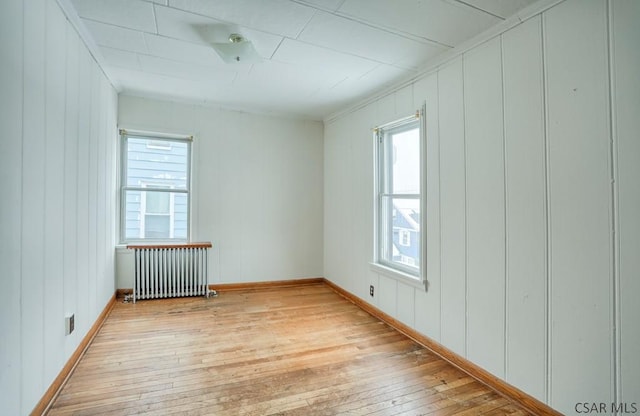 empty room with radiator heating unit and light hardwood / wood-style floors