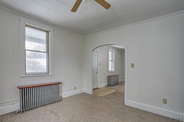 empty room featuring crown molding, light carpet, radiator heating unit, and ceiling fan