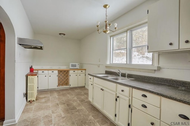 kitchen with pendant lighting, ventilation hood, a chandelier, and sink