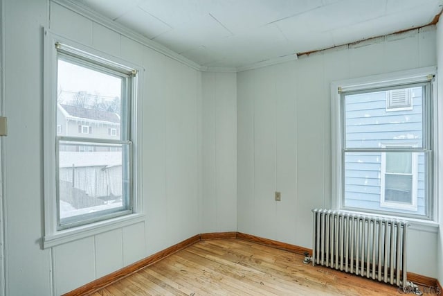 unfurnished room with radiator, crown molding, and light wood-type flooring