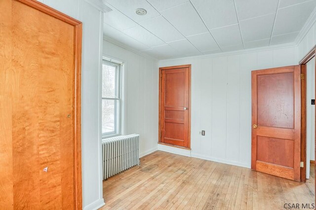 unfurnished bedroom featuring crown molding, radiator, and light hardwood / wood-style flooring