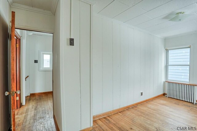 hallway with ornamental molding, radiator heating unit, and light hardwood / wood-style floors