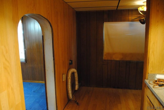 hallway with hardwood / wood-style floors, a paneled ceiling, and wooden walls